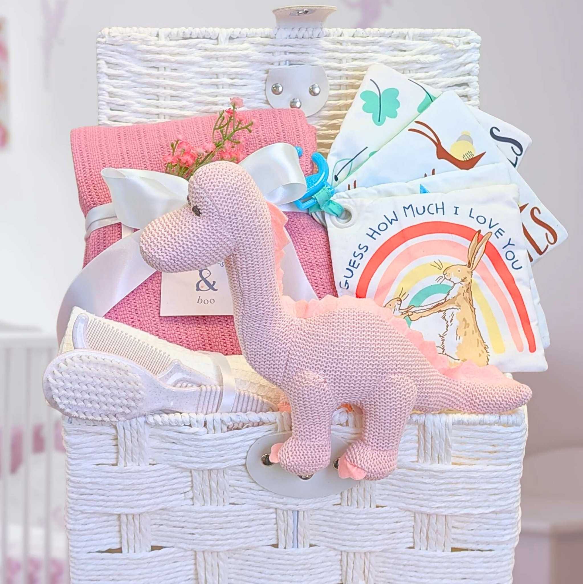 Gift hamper for a new baby girl with organic dinosaur rattle, soft book and cosy essentials.