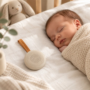 Taupe Drift Away white noise machine with tan loop, displayed beside its box and instruction booklet.