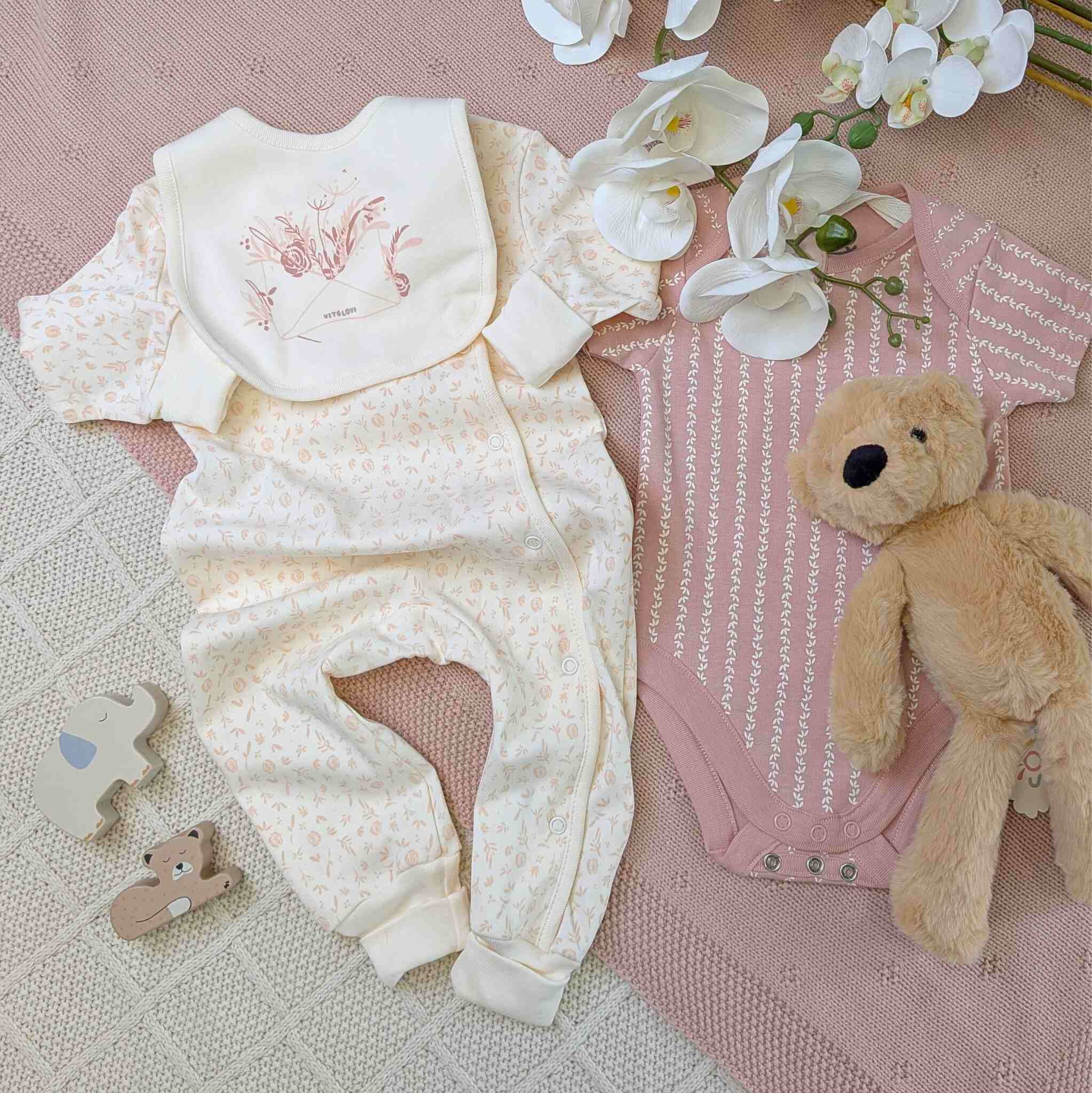 Baby outfit with white floral design, dusky pink vest and baby bib.