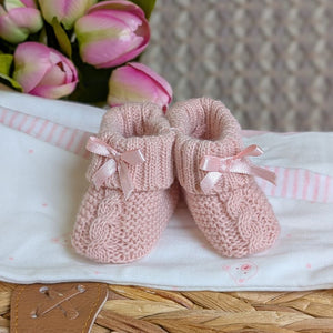 Pair of pink knitted baby booties with ribbons.