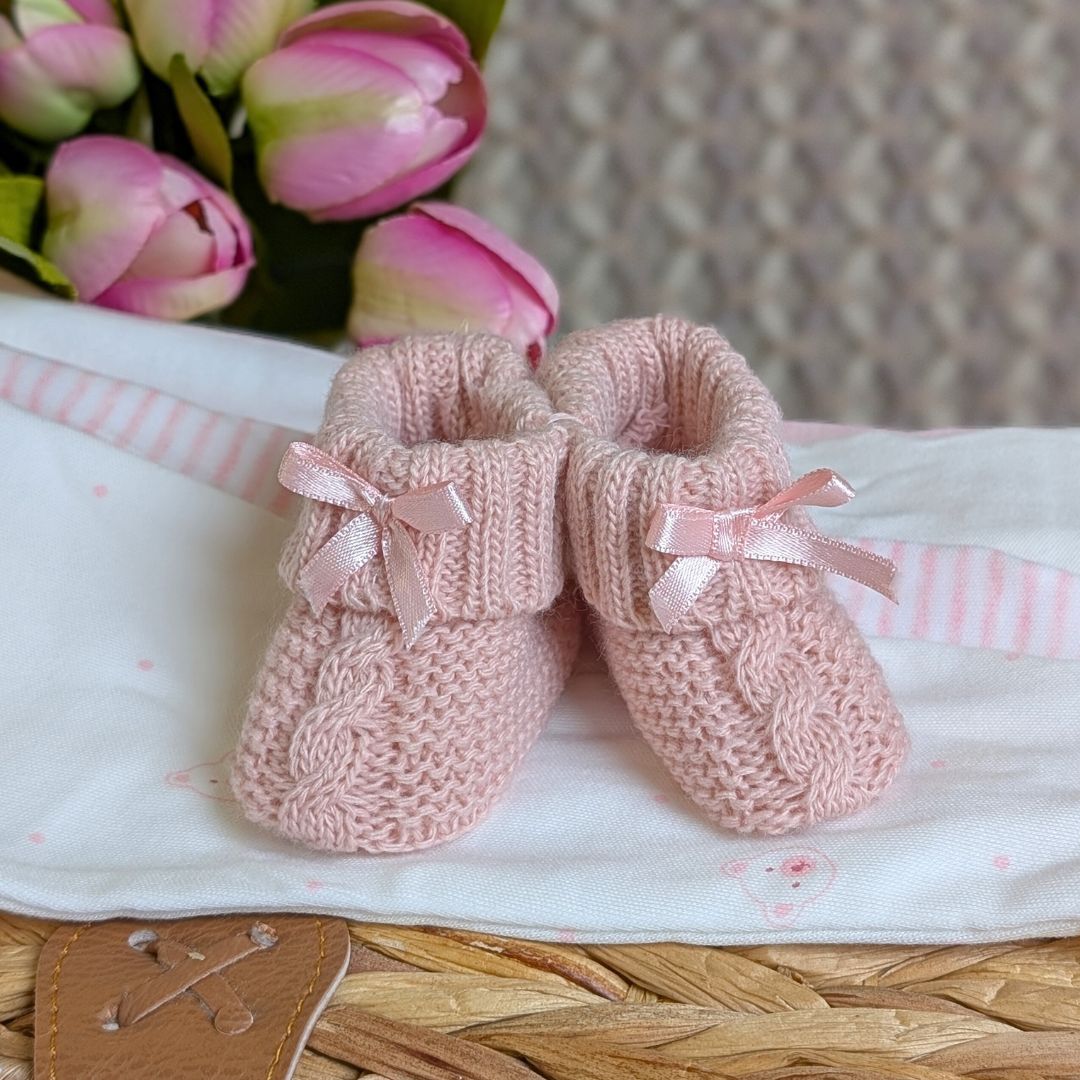 Pair of pink knitted baby booties with ribbons.