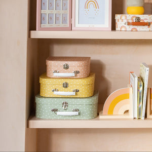 earth tones spotted suitcase set styled on nursery shelf