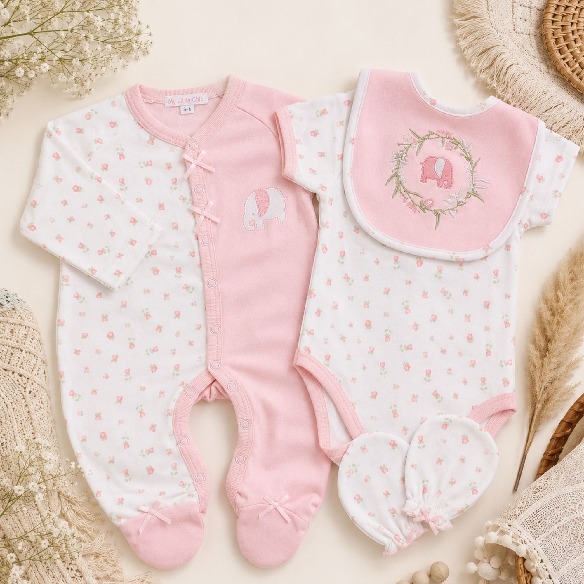 Set of pink baby clothes including romper, vest and baby bib.
