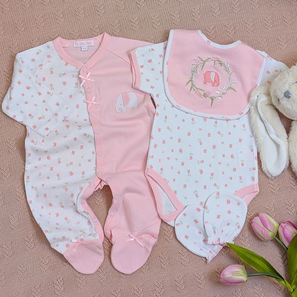 Set of pink baby clothes including romper, vest and baby bib.