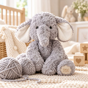 A plush grey elephant toy with cream-colored ears