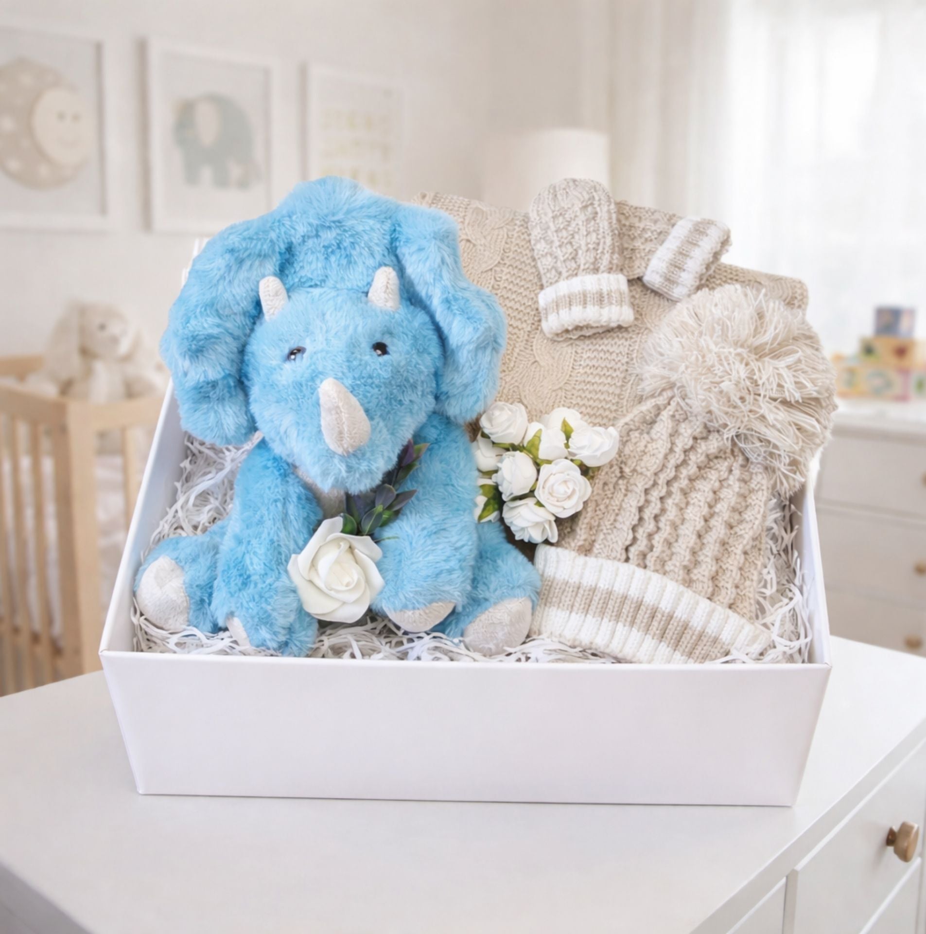 A baby boy gift idea in a box with dinosaur and knit hat and blanket set.