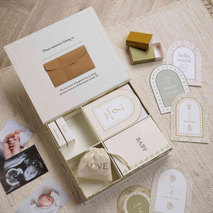 Open filled baby memory box with record booklet, pouch and mini boxes, alongside milestone cards.