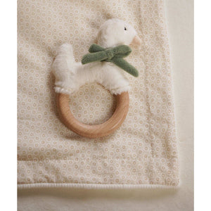 Close view of a plush goose with sage bow and wooden teething ring on the blanket’s floral reverse.