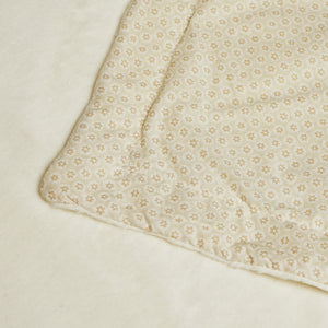 Close-up of the baby blanket’s small floral reverse, stitched edge and plush cream surface.