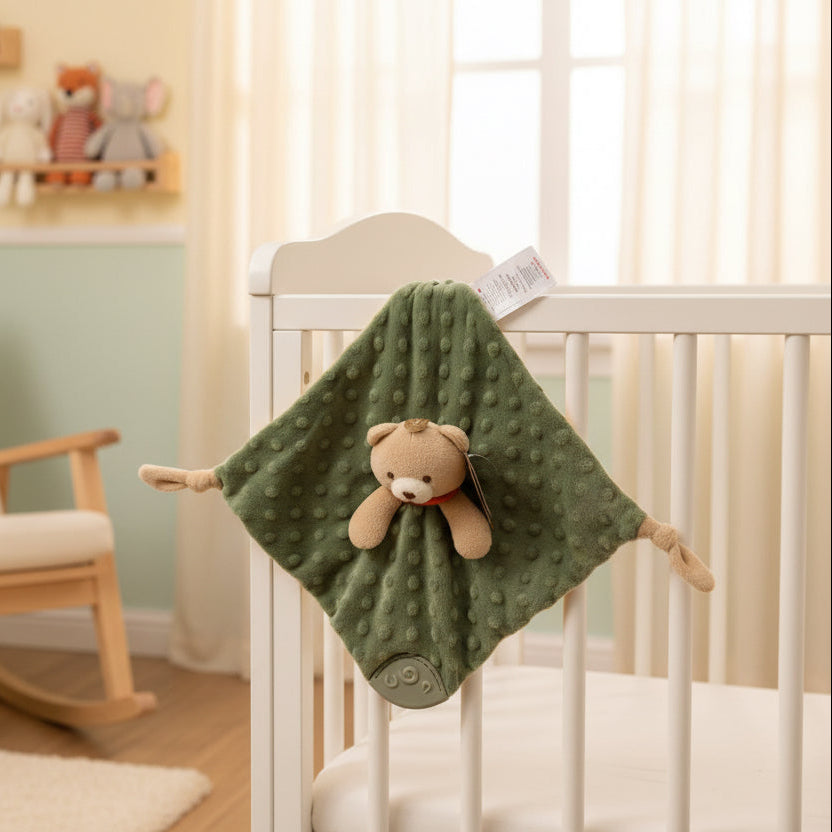 Sage green newborn baby comforter with knots and a teethers at the corners and an attached teddy plush toy