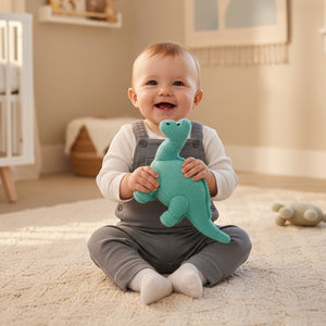bright turquoise blue dinosaur baby rattle, this large rattle is being held by a baby