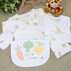 a baby clothing set with bib, hat and romper which says keep growing