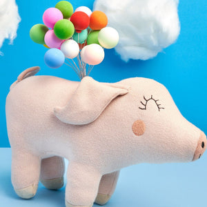 Knitted organic cotton pig soft toy with stitched smile and floppy ears, suitable for babies.