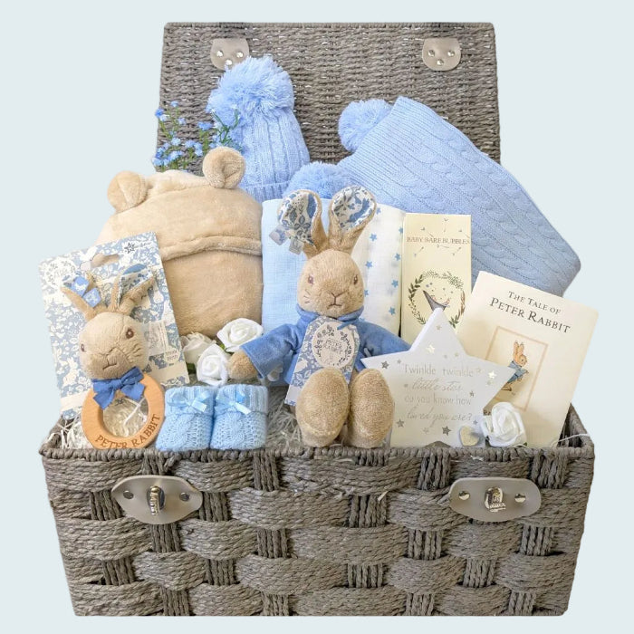 Large baby boy hamper with gifts including peter rabbit toy, beige blanket, journal and clothing.