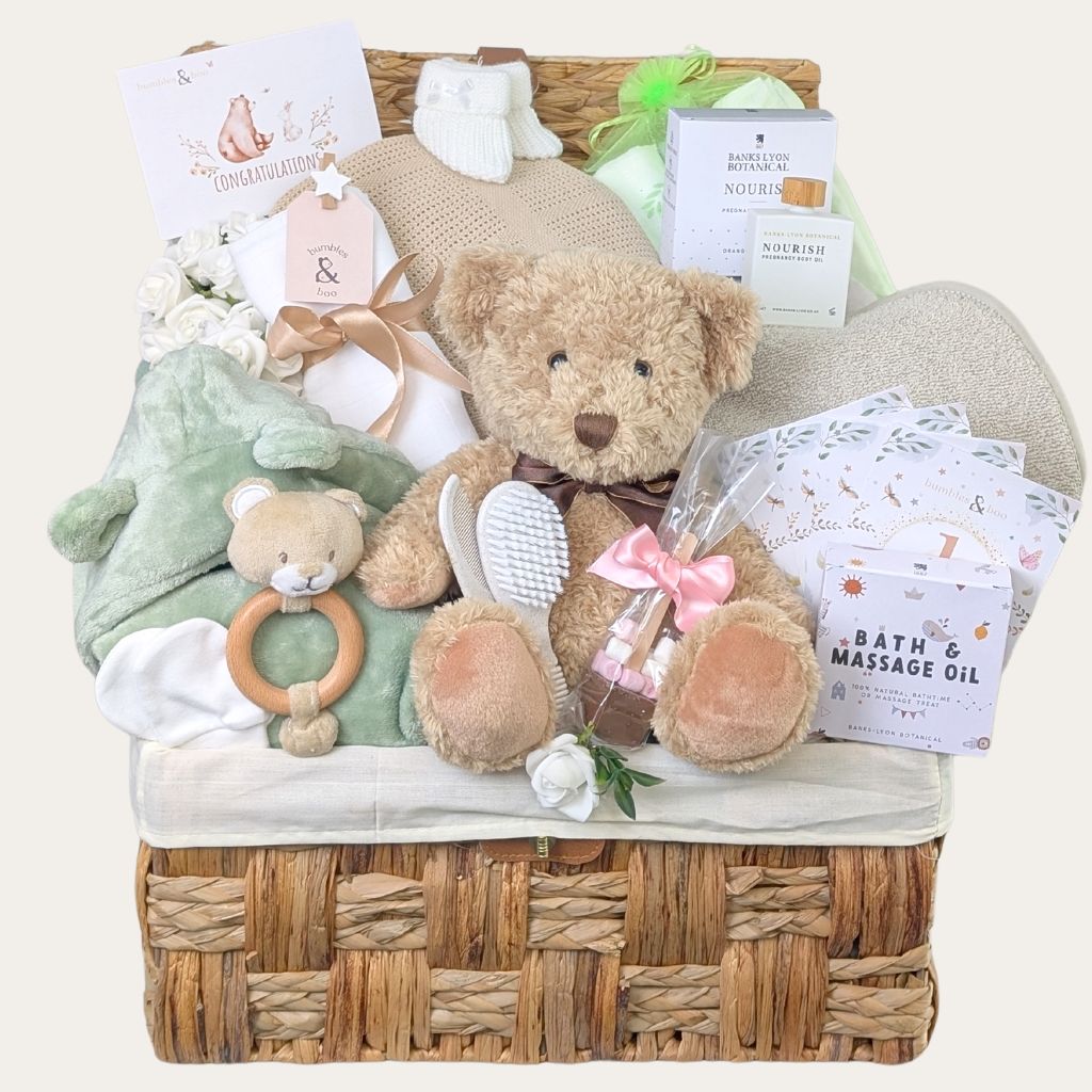 Mum to be gifts hamper with presents of pregnancy oil for expectant mums, chocolate treats and baby essentials in a woven basket