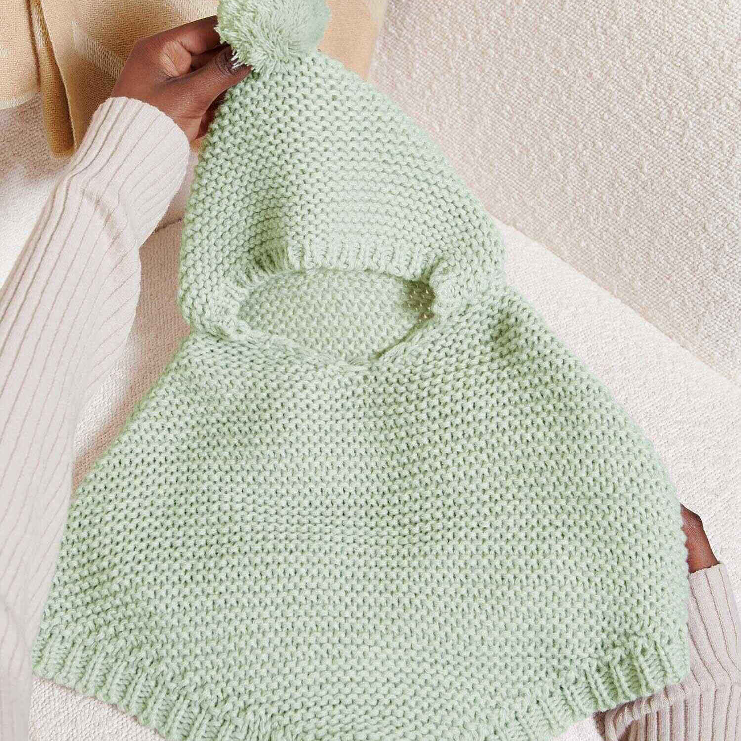 Light sage knitted baby poncho with pom pom hood