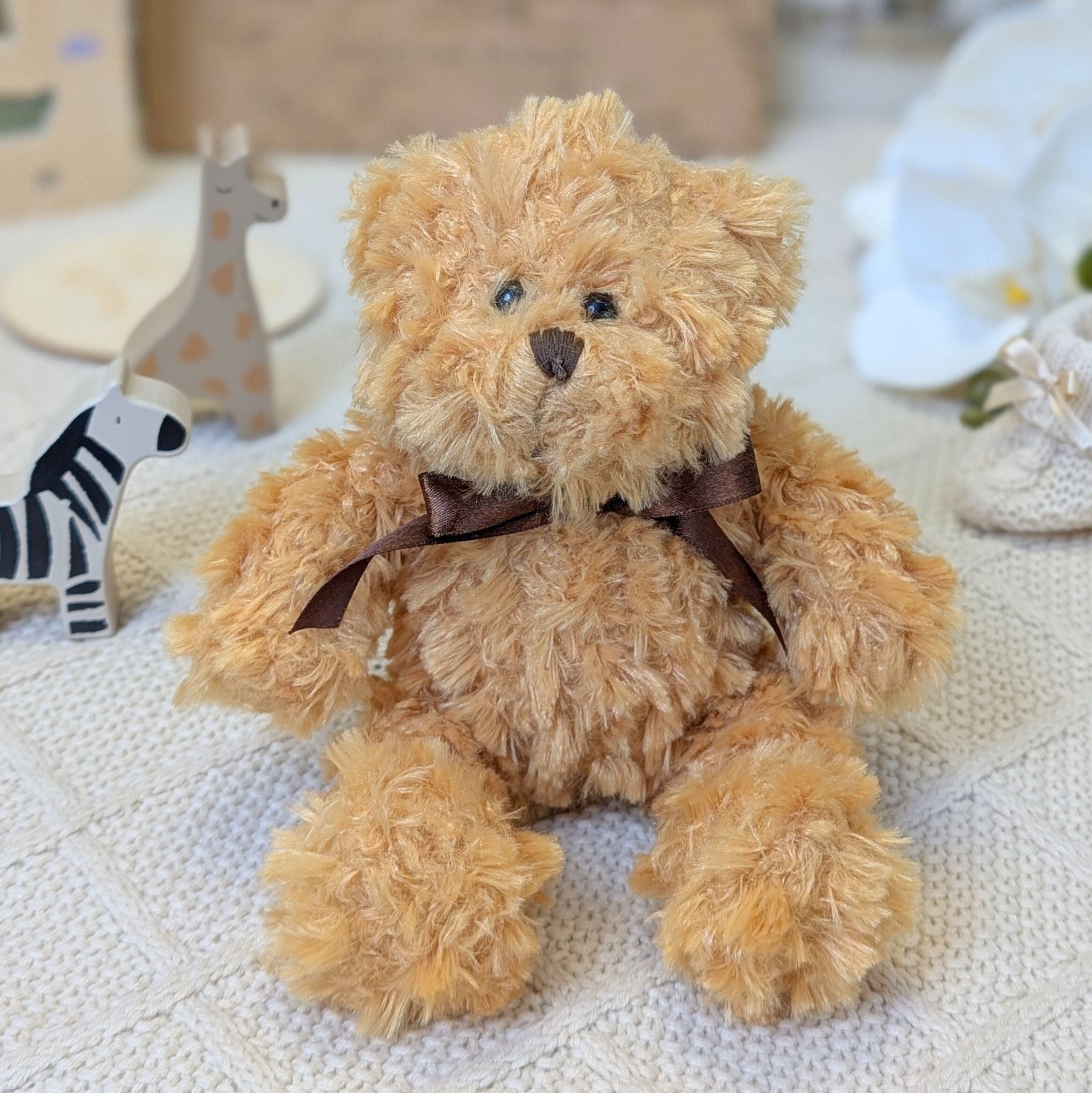 Brown teddy bear, small and brown with a brown bow