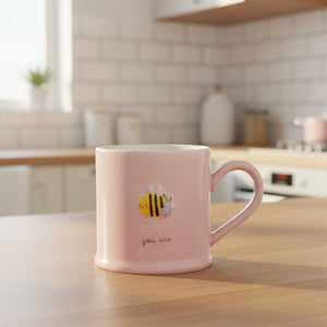 Pink ceramic Mummy Bee-utiful mug with embossed bee and printed sentiment on kitchen table, new mum gift idea.