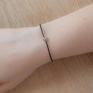 Mummy to be wish bracelet worn on the wrist with a heart charm and black cord.