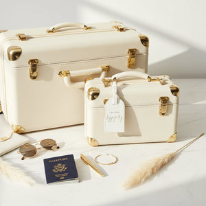 White My First Luggage Tag in vegan leather with gold lettering attached to cream suitcase, travel accessory for new mum gifts.