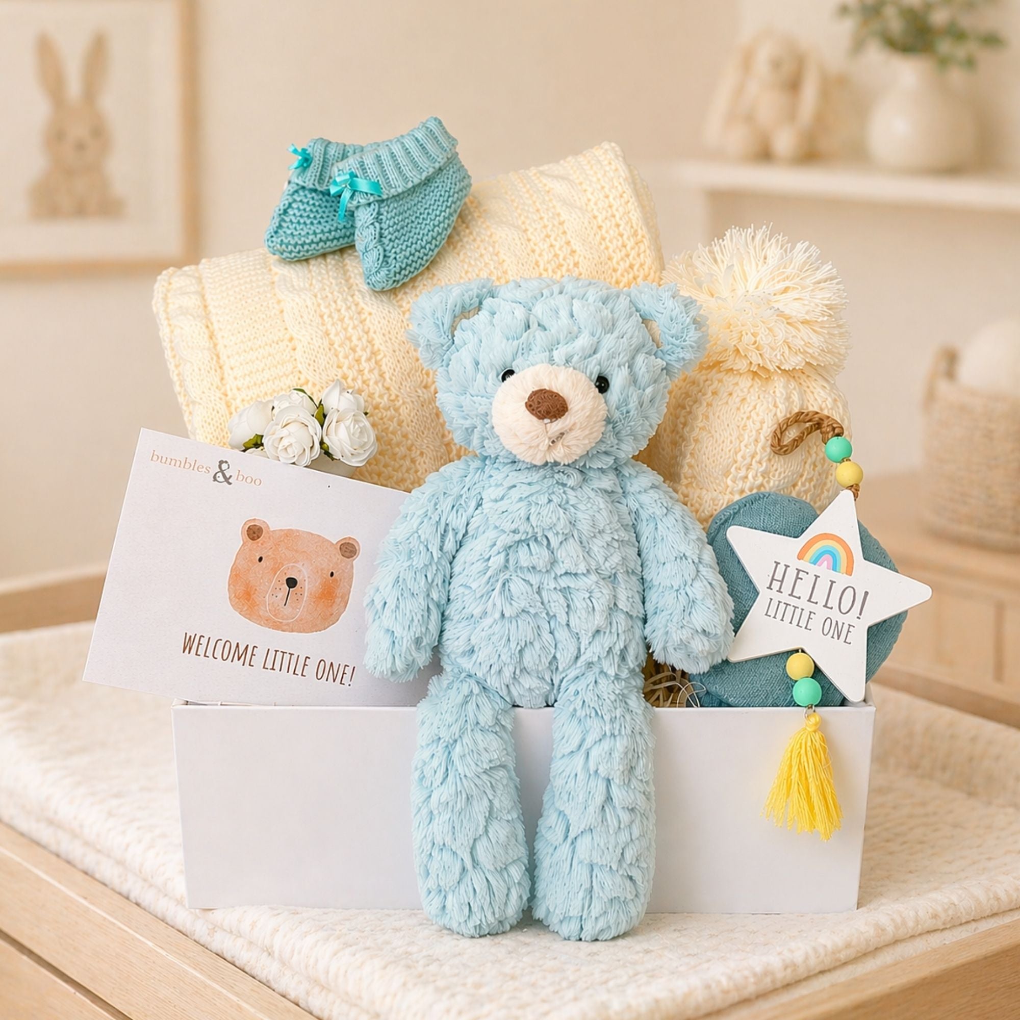 Hamper box for a new baby with mint teddy bear and cream hat and blanket.