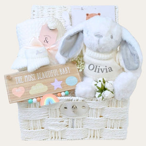 New baby gifts basket with white presents to welcome a new baby.