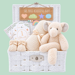 New baby hamper basket with a cream elephant theme and bamboo blanket presented in a white basket.