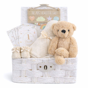 New baby hamper with a teddy bear and blanket in a white basket.