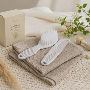 Ivory baby brush and comb with ribbed handles displayed on folded neutral fabric.
