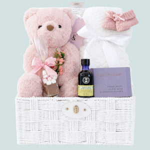 New mum gifts basket with pink teddy bear and white blanket for baby.