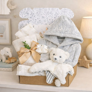 A grey and white baby gift box with personalised dressing gown and teddy bear comforter.