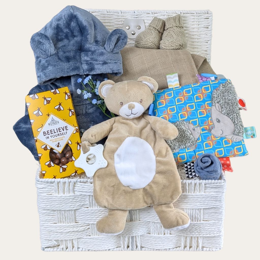 Newborn baby boy hamper basket with gifts including a blue dressing gown, taggie toy and comforter. Designed by Bumbles and Boo.
