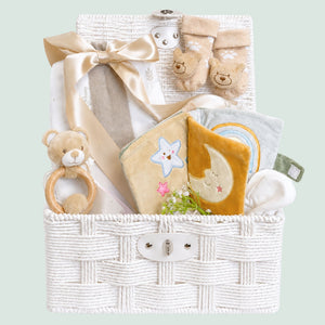 Newborn baby gifts in a hamper basket. Presents include soft book and a unisex beige theme.