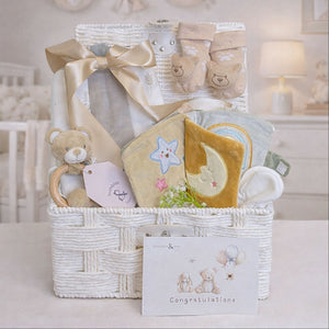 Newborn baby gifts in a hamper basket. Presents include soft book and a unisex beige theme.