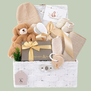 Newborn baby gifts hamper basket with teddy bear, hat, and other items in a white hamper