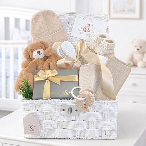Newborn baby gifts basket with teddy bear, hat, and other items in a white hamper