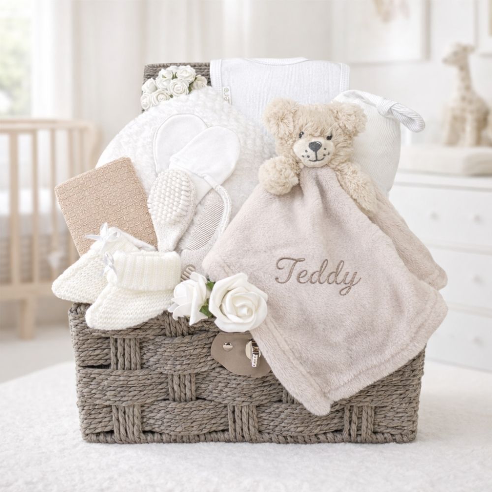 Newborn presents in a gift basket with beige and white baby essentials and teddy comforter