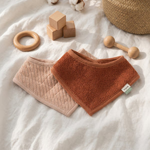 Hush Rose bandana bibs in pale pink and rust, with their pointed fronts overlapping.