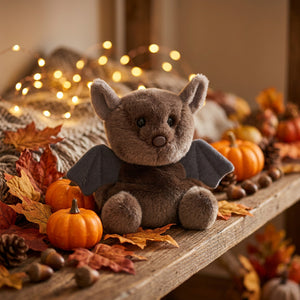 Palm Pals Luna Bat seated among small pumpkins and autumn leaves with dark wings spread.