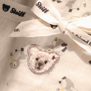 Close-up of the cotton burp cloth showing penguin illustrations, teddy bear embroidery and a tied ribbon.