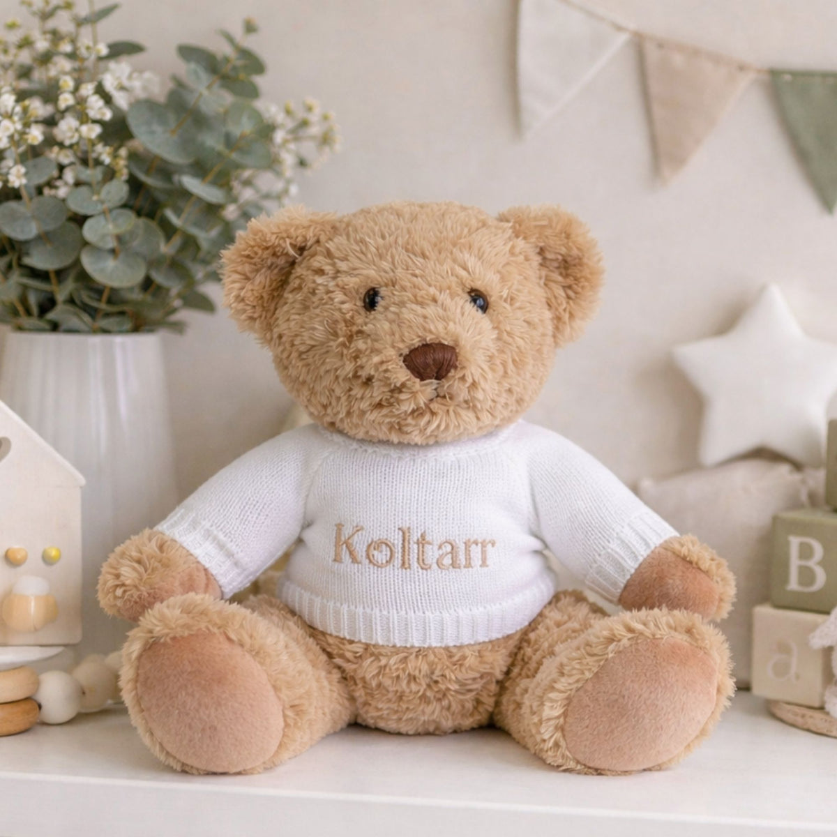 Personalised brown baby teddy bear wearing a white personalised jumper with the name Koltar