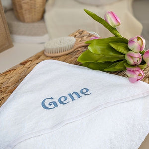 Personalised baby bath towel in white, customised with the name ‘Gene’ embroidered across the hood.