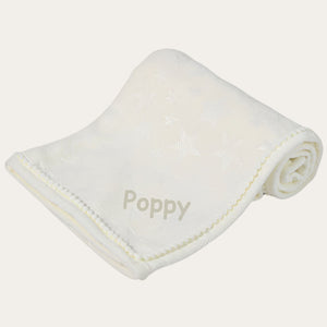 A personalised white baby blanket with a star design and little pompoms.