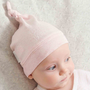 Pink organic cotton baby knot hat with adjustable top knot and ribbed band, soft newborn baby clothes hat in gentle blush fabric.