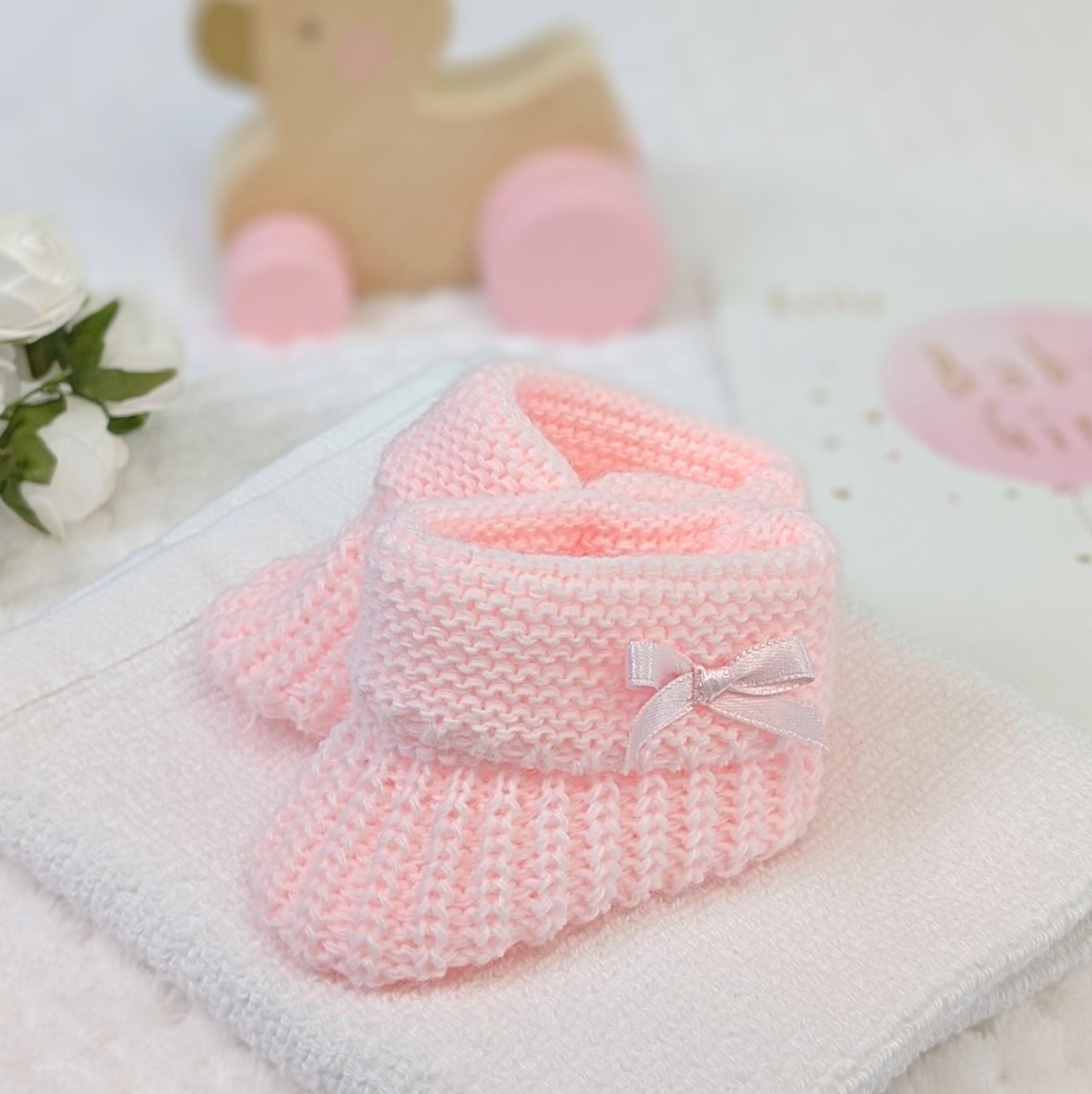 Pink plain knit baby booties with side bow suitable for 0-6 months.