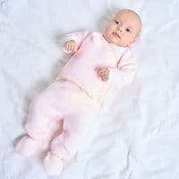 Baby lying on a white blanket wearing the pink wrap cardigan and matching footed leggings.