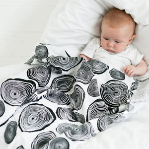 Organic Baby Muslin featuring black and white circle print, designed to stimulate baby brain function and development. Made from 100% organic cotton. Shown with baby.