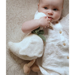 Baby holding the plush goose with its beige feet visible