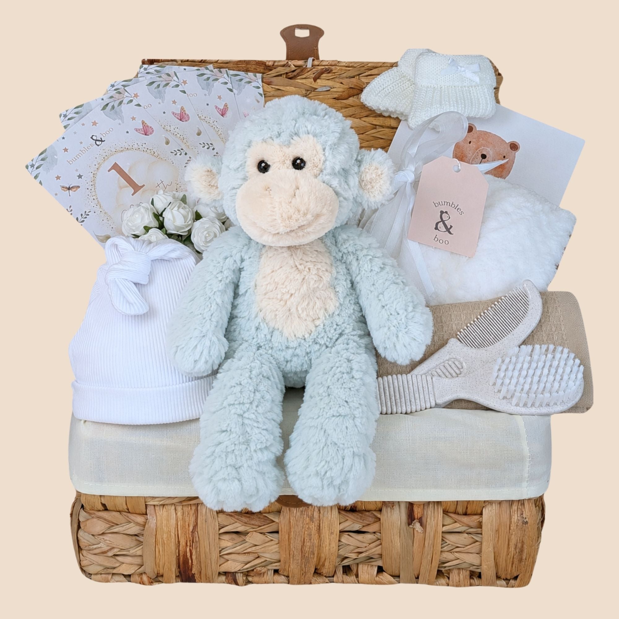 Baby shower gifts hamper with a white neutral theme packed in a basket. Designed by Bumbles and Boo.