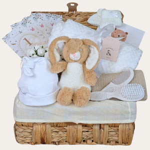 Baby shower gifts hamper with a white neutral theme packed in a basket. Designed by Bumbles and Boo.